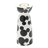 Ceramic tealight candle holder in white with black Mickey Mouse head shapes, rounded cup top with gold-toned insert, narrow waist, and flared base, on a plain white background.