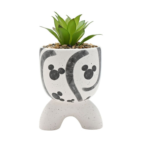 Ceramic planter in speckled white with grey Mickey Mouse head motifs and swirls, set on arched feet, holding a faux succulent plant, on a plain white background.