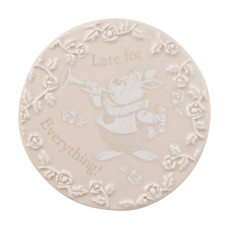 Round cream stoneware coaster with raised white rose border, engraved White Rabbit blowing a trumpet and "Late for Everything!" text, from the Alice in Wonderland set, on a white background.