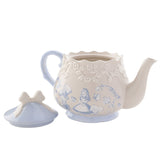 Beige stoneware teapot with light blue Alice and Mad Hatter decals, raised rose band, scalloped rim, and bow-handled lid resting beside it on a white background.