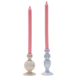 Set of two ceramic taper candle holders with pink candles, one pale blue tiered holder with Alice's silhouette, one beige holder with the White Rabbit, on a white background.
