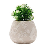 Beige ceramic mini planter with scalloped rim and raised white Alice in Wonderland silhouette, filled with faux greenery and white flowers, on a white background.
