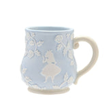 Blue earthenware mug with embossed white roses and leaves, featuring a raised white Alice in Wonderland silhouette and cream handle, set against a plain white background.