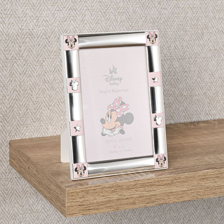 Minnie Mouse 6x4in silverplated photo frame in pink and silver, with corner Minnie motifs and star and mouse-ear tiles, shown upright on a wooden shelf.