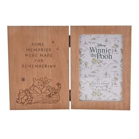 Hinged wooden photo frame in brown wood grain, left panel engraved with "Some memories were made for remembering" and Winnie the Pooh, Piglet and Tigger on a log, right panel holds a 6"x4" photo.
