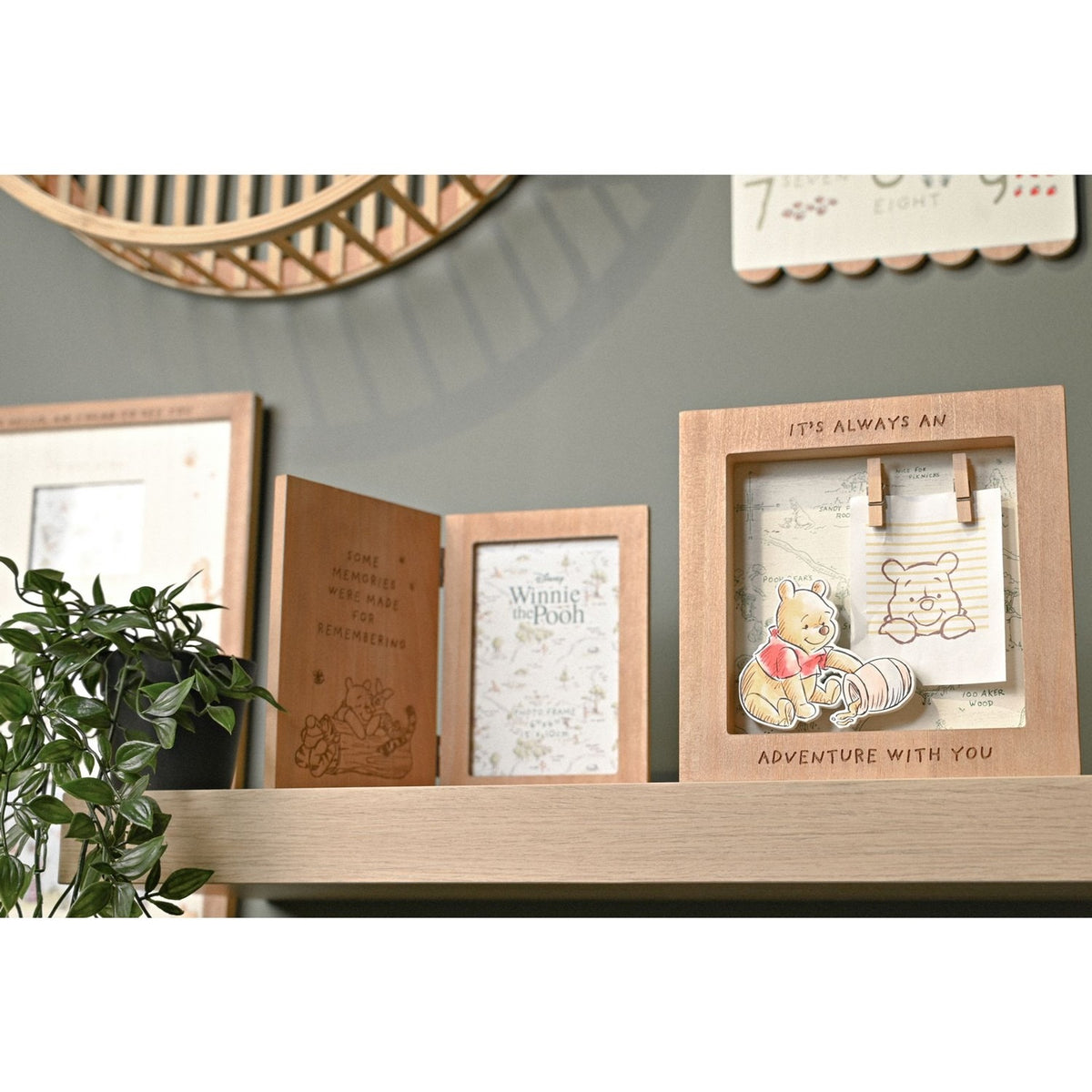 Square brown wooden box photo frame with "It's always an adventure with you" lettering, a Pooh map print, pegs, and a raised Pooh cut-out, shown on a shelf.