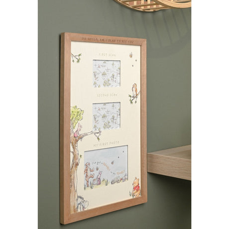 Winnie the Pooh multi aperture scan frame in brown wood with off-white mount, three labelled openings for first scan, second scan and first photo, shown mounted on a green wall.