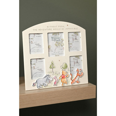 White wooden multi-aperture photo frame with arched top, five openings, gold-toned quote, and Winnie the Pooh characters along the base, shown on a wooden shelf.
