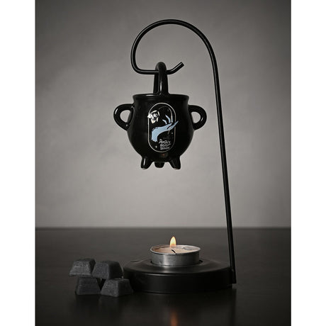 Nightmare Before Christmas black ceramic wax melt burner shaped as a cauldron with handles, hung from a tall curved stand over a lit tealight, with wax melts beside it.