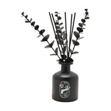 Nightmare Before Christmas reed diffuser in a rounded black bottle with black reeds, gold-edged label featuring Sally's Deadly Night Shade design, on a white background.
