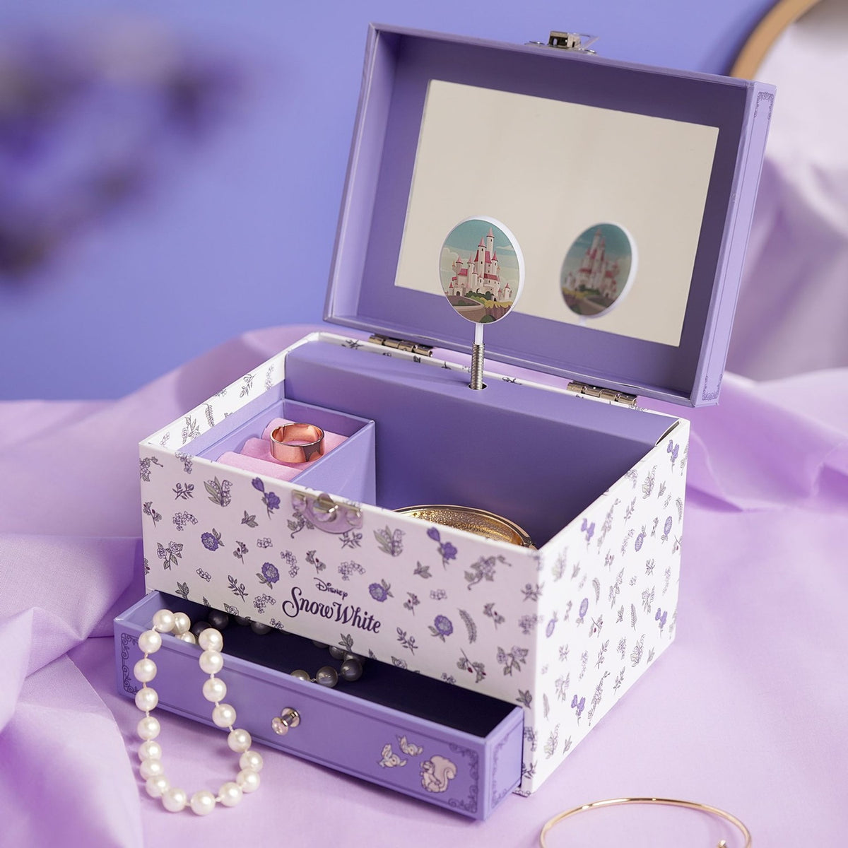 Snow White Musical Jewellery Box, open rectangular lilac and white floral-print case with mirror, spinning castle charm, divided tray, ring, pearl necklace and pull-out drawer.
