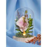 Light-up glass cloche on wooden base with pink and white bloom, foliage, gold spiral accents, glowing LED flame, and gold princess silhouette decal.