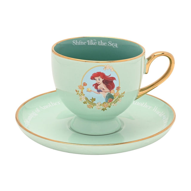 Pastel green porcelain tea cup and saucer with gold handle and rim, featuring a printed Ariel decal in a floral oval and "Shine like the Sea" on the inner rim, shown on a white background.
