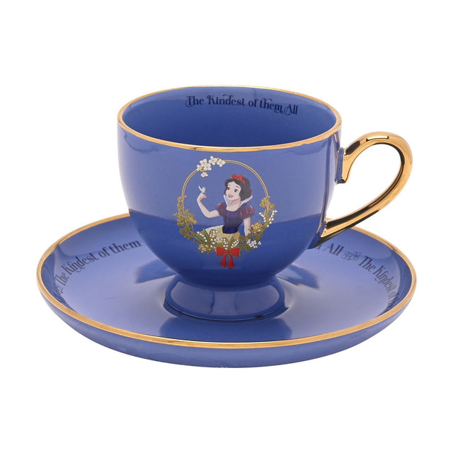 Purple porcelain tea cup and saucer with gold rim and handle, featuring Snow White in a floral wreath and "The Kindest of them All" script, on a white background.