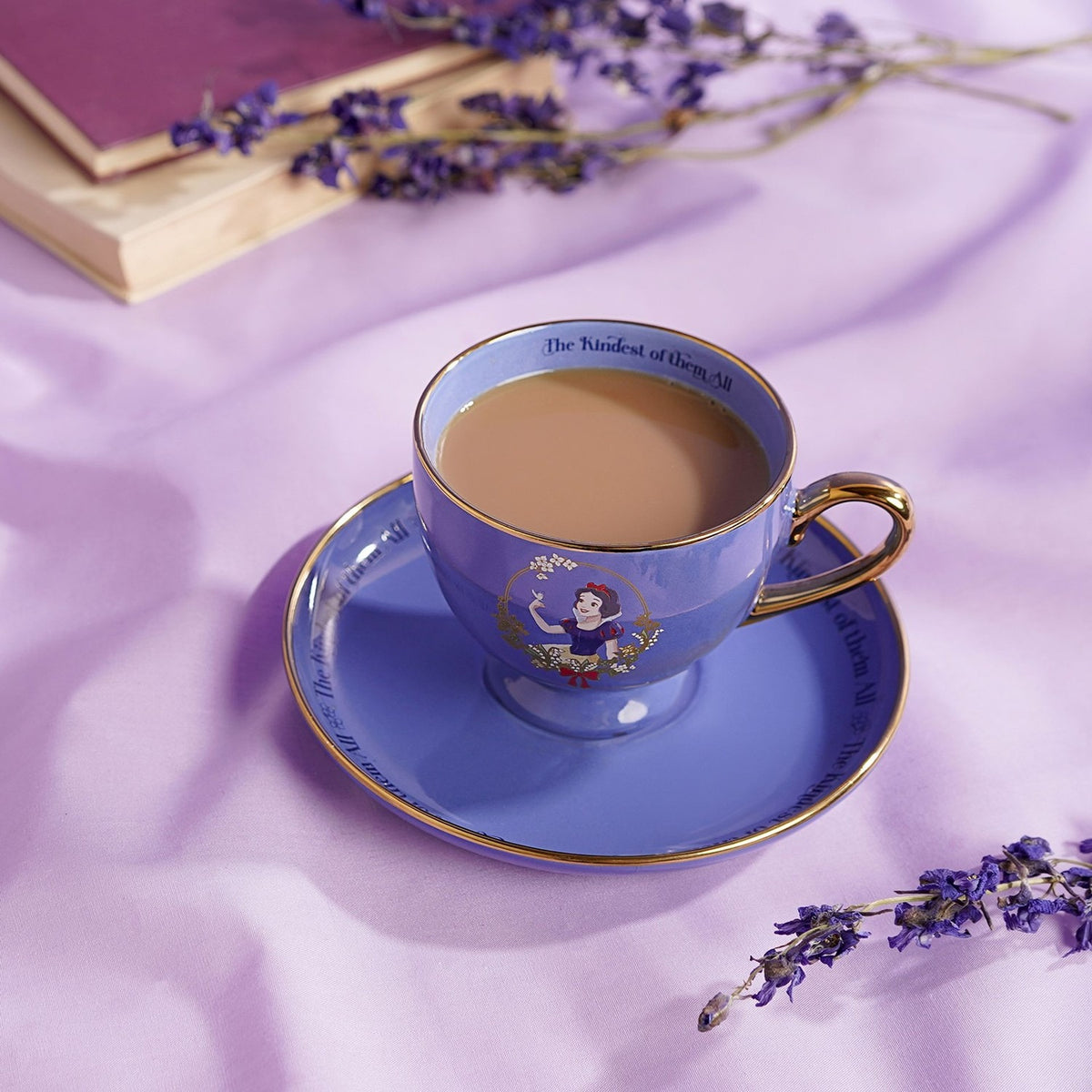 Snow White Pastel Princess porcelain tea cup and saucer in purple with gold trim, filled with tea, Snow White motif on cup, styled with dried lavender and a book.