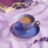 Snow White Pastel Princess porcelain tea cup and saucer in purple with gold trim, filled with tea, Snow White motif on cup, styled with dried lavender and a book.