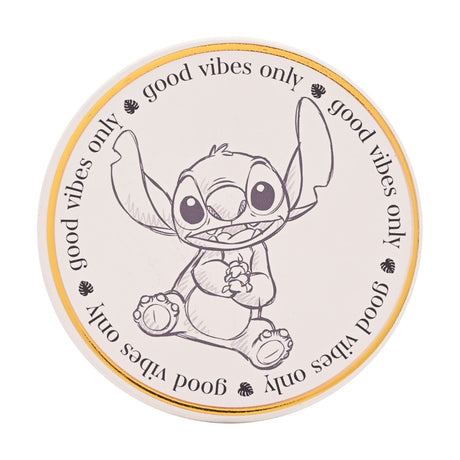 Round white stoneware coaster with gold rim, featuring a sketched Stitch sitting with raised ears and paws together, bordered by "good vibes only" text and leaf motifs, on a plain background.