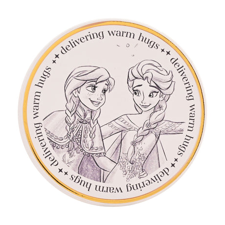 Round white stoneware coaster with a grey and lilac pencil-sketch of Anna and Elsa from Frozen, framed by a gold rim and "delivering warm hugs" lettering on a plain background.