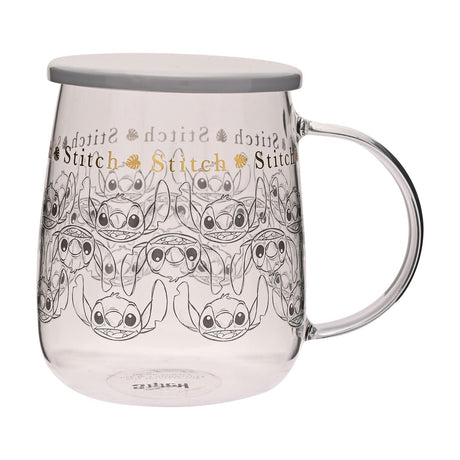 Clear glass mug with handle and flat grey lid, printed with repeating grey-line Stitch faces and a gold "Stitch" lettering band with small leaves, shown on a plain white background.