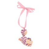 Resin Cheshire Cat hanging Christmas tree decoration, pale pink with purple stripes, lying stretched out with a pink ribbon hanger, on a plain white background.