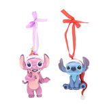 Set of 2 hanging resin Christmas tree decorations featuring Angel in pink and Stitch in blue, both wearing Santa hats, with ribbon loops on a white background.