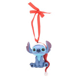 Stitch hanging resin Christmas tree decoration, seated in blue with pale blue eye patches, wearing a red and white Santa hat, on a red ribbon against a plain white background.