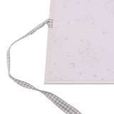 Close-up of the Ohana Stitch Baby Photo Album's corner, showing a cream cover with faint pastel character and star motifs, tied with a grey gingham ribbon.