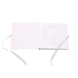 Open Ohana Stitch baby photo album showing a "hello world" record page with fill-in details, grey gingham ribbon ties, and a pale star-patterned inner cover.