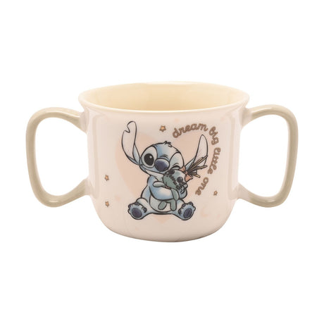 Cream porcelain baby mug with two sage-green handles, featuring Stitch hugging a green rag doll and "dream big little one" script, shown on a plain white background.