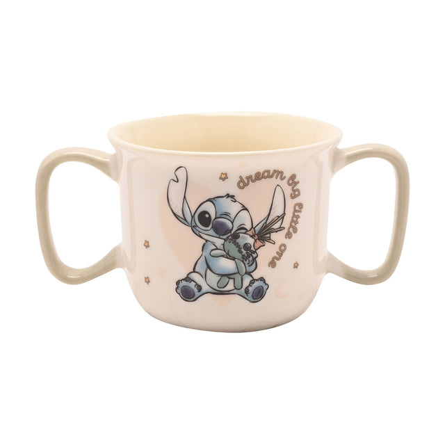Cream porcelain baby mug with two sage-green handles, featuring Stitch hugging a green rag doll and "dream big little one" script, shown on a plain white background.