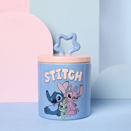 Round blue stoneware Stitch storage jar with pink lid and wavy star knob, "STITCH" in raised pink letters above Stitch and a pink companion with a green ragdoll.