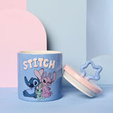 Blue stoneware storage jar with raised "STITCH" lettering and printed Stitch, Angel and Scrump design, lid removed showing pink disc with star-shaped knob.