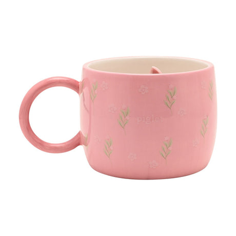 Pink stoneware mug with round handle, floral and leaf sprig pattern, "piglet" lettering, and white interior revealing a sculpted Piglet figure inside, shown on a plain white background.