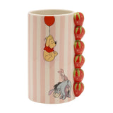 Stoneware vase in pink and cream stripes with a raised red strawberry column handle, featuring Winnie the Pooh under a balloon, Piglet and Eeyore, on a white background.