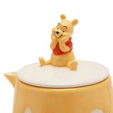 Winnie the Pooh Honey Pot stoneware teapot in cream and yellow, close-up of the lid with a seated Pooh figure in a red shirt, shown on a white background.