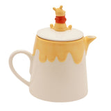 Winnie the Pooh Honey Pot stoneware teapot in cream with a yellow drip glaze, curved handle, spout, and a white lid topped with a seated Pooh figure, shown on a plain white background.