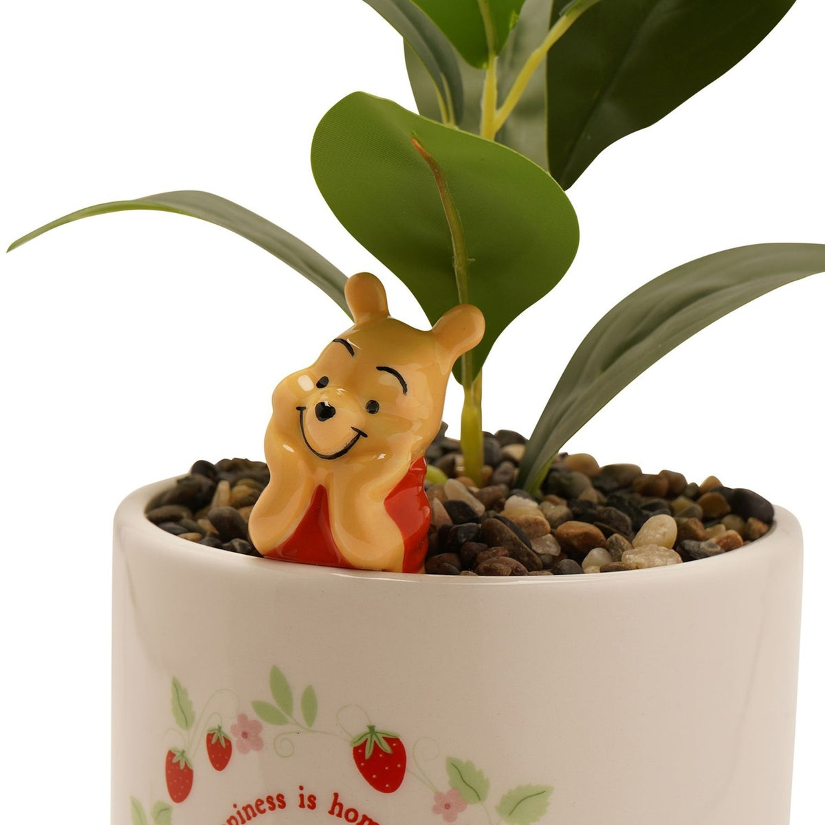 Close-up of the Winnie the Pooh stoneware planter in cream, showing the 3D Pooh figure resting his chin on his paws amid pebbles and a faux plant, with strawberry and floral print below.