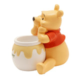 Winnie the Pooh Honey Pot resin storage box in pale yellow and white, bear leaning on open pot with "hunny" text and yellow drip detail, red top, plain white background.