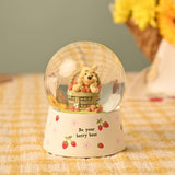 Winnie the Pooh Basket Snow Globe with Strawberries in cream resin, showing Pooh in a woven basket with strawberries inside a clear glass globe on a floral cream base reading "Be your berry best".