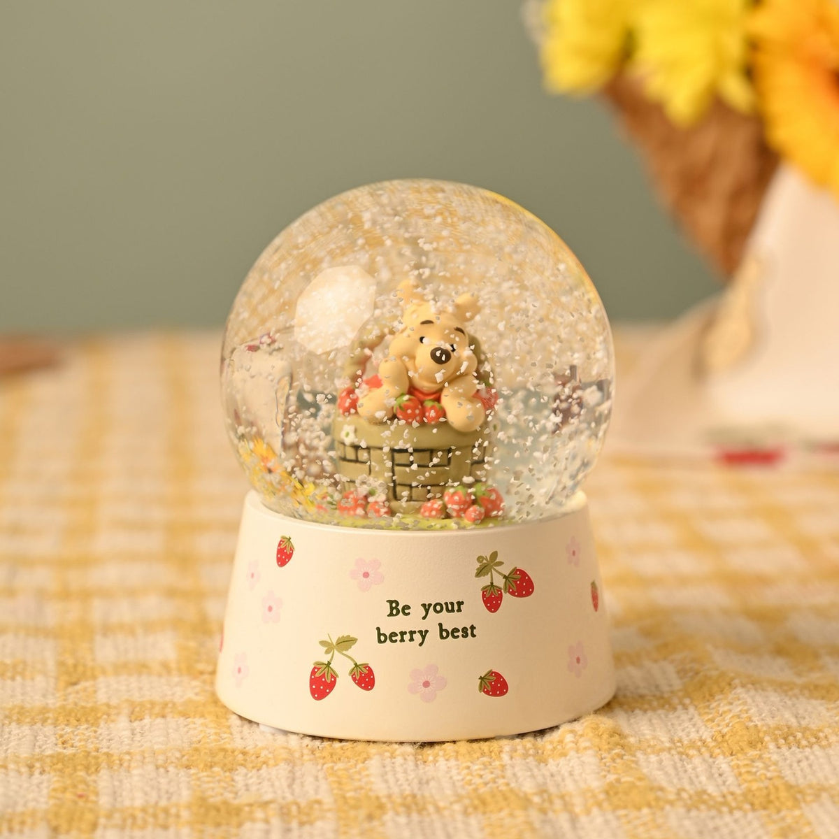 Winnie the Pooh Basket Snow Globe with Strawberries in cream resin, showing Pooh peeking over a strawberry-filled basket inside the glass globe on a cream base reading "Be your berry best".