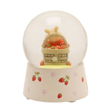 Winnie the Pooh snow globe featuring a figure peeking from a woven strawberry basket inside a clear glass globe, set on a cream base with strawberry and floral accents.