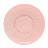 Pink porcelain saucer from the Piglet cup and saucer set, featuring "It's always better together" printed in pink script around the rim on a plain background.