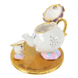 Mrs Potts and Chip Teapot Trinket Box with hinged lilac-gold lid open, white teapot with gold handle and jewels beside a small teacup on a round gold base, plain white background.