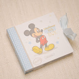 Mickey Mouse Handsome Little Boy Photo Album, 6 x 4in, with pale blue polka dot spine and sketched Mickey cover, tied with a ribbon on a neutral woven background.