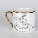 White porcelain mug with gold rim and handle, featuring a pencil-style sketch of Belle in her ball gown holding a teacup, on a plain light background.
