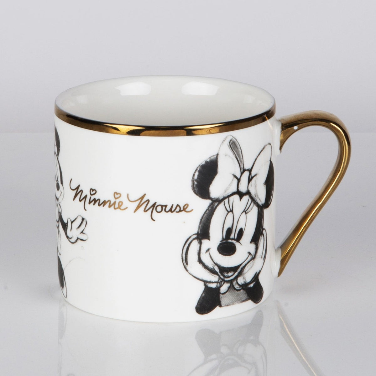 White gloss porcelain mug with gold rim and handle, featuring pencil-style sketches of Minnie Mouse and "Minnie Mouse" in gold script, shown on a plain light background.