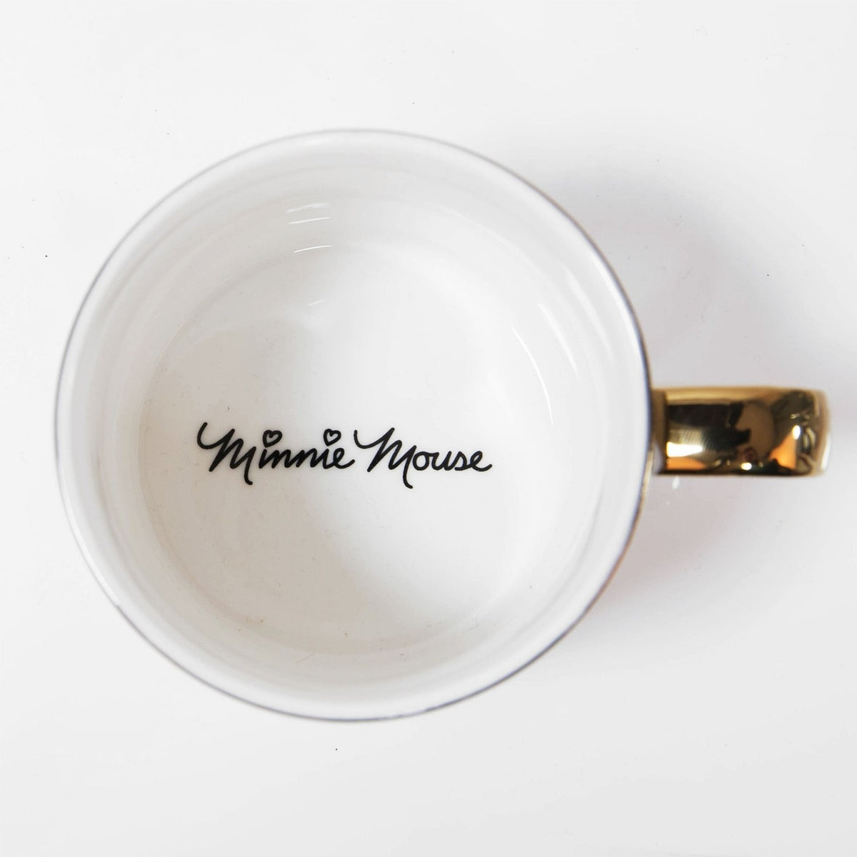Top-down view of the Minnie Mouse Classic Collectable gloss porcelain mug in white, showing "Minnie Mouse" in black script inside the cup and a glossy gold handle.