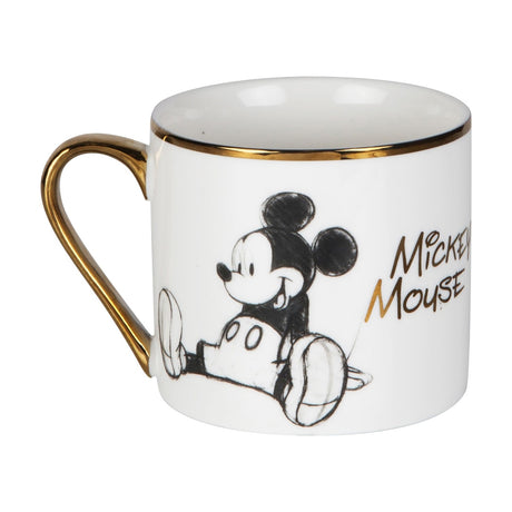 White porcelain mug with gold rim and handle, featuring a sketch-style Mickey Mouse sitting and "Mickey Mouse" lettered in gold, shown on a plain white background.