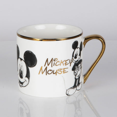 White porcelain mug with sketch-style Mickey Mouse illustrations in black, gold "Mickey Mouse" lettering, gold rim and handle, shown on a plain white background.