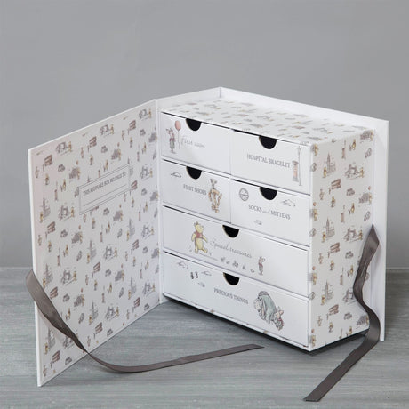 Christopher Robin Bear of Very Big Heart cream keepsake box, open to reveal six labelled drawers with sketched print and grey ribbon ties, shown against a plain grey background.